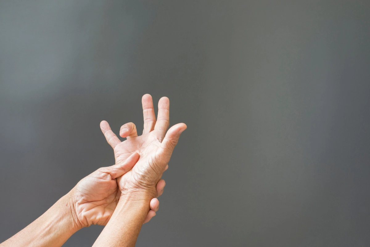 Hands against a gray background demonstrating a Trigger Finger. A defect in a tendon causing a finger to jerk or snap straight when the hand is extended.