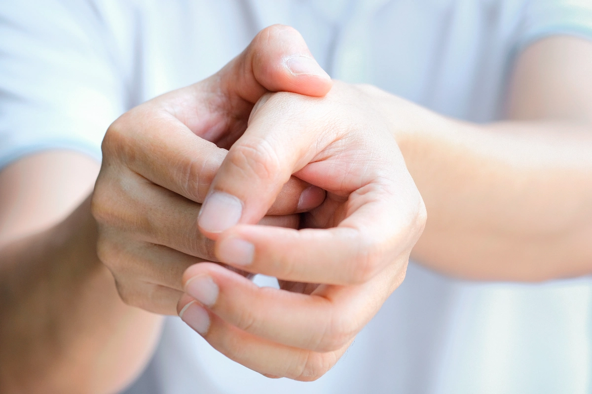 Two hands, one pressing the thumb of the other, suggesting a gesture of self-care or relief. Soft lighting creates a calm and focused mood. De Quervain's Tenosynovitis Surgery Dr. French Vancouver