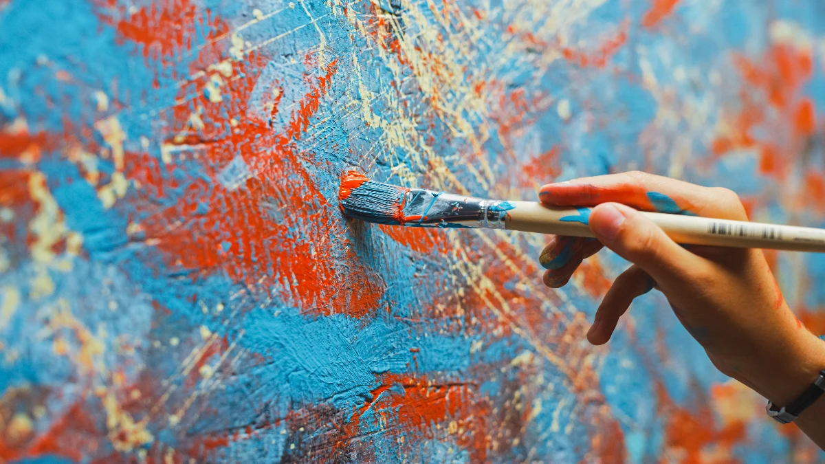 Photo of a hand with paint brush. Painting a canvas with abstract colours of blue and red. Hand Surgeon for Artists Dr. Rod French Vancouver, BC