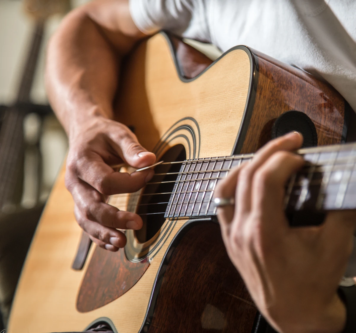 Photo of a person playing acoustic guitar, cropped to show just hands and body of guitar. Hand Surgeon for Musicians, Dr. Rod French, Vancouver, BC